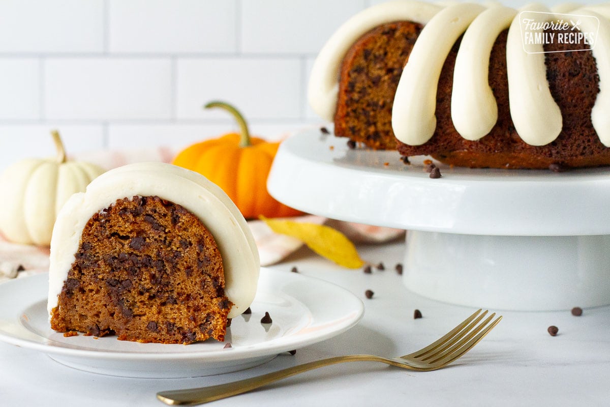 Pumpkin Bundt Cake slice on a plate next to a whole Pumpkin Bundt Cake on a cake stand.