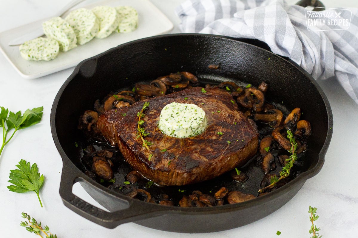 Cast Iron skillet with Herbed Butter on a steak and mushrooms.