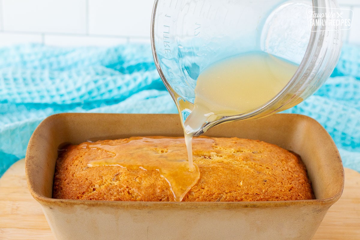 Glaze pouring onto Sweet Coconut Bread in a baking dish.