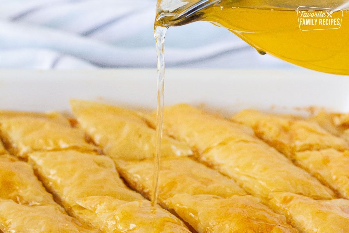 Honey lemon syrup pouring on top of hot Baklava.