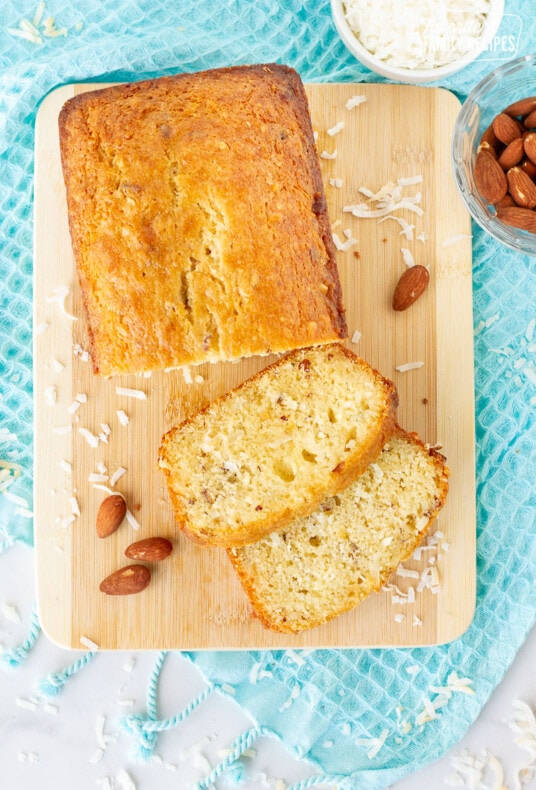 Two slices of Sweet Coconut Bread on a cutting board with a loaf.