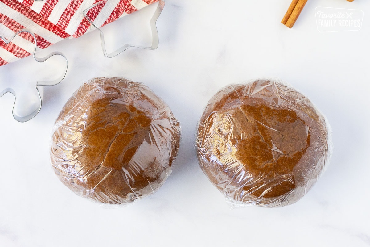 Two balls of Gingerbread Cookie dough wrapped in plastic wrap.