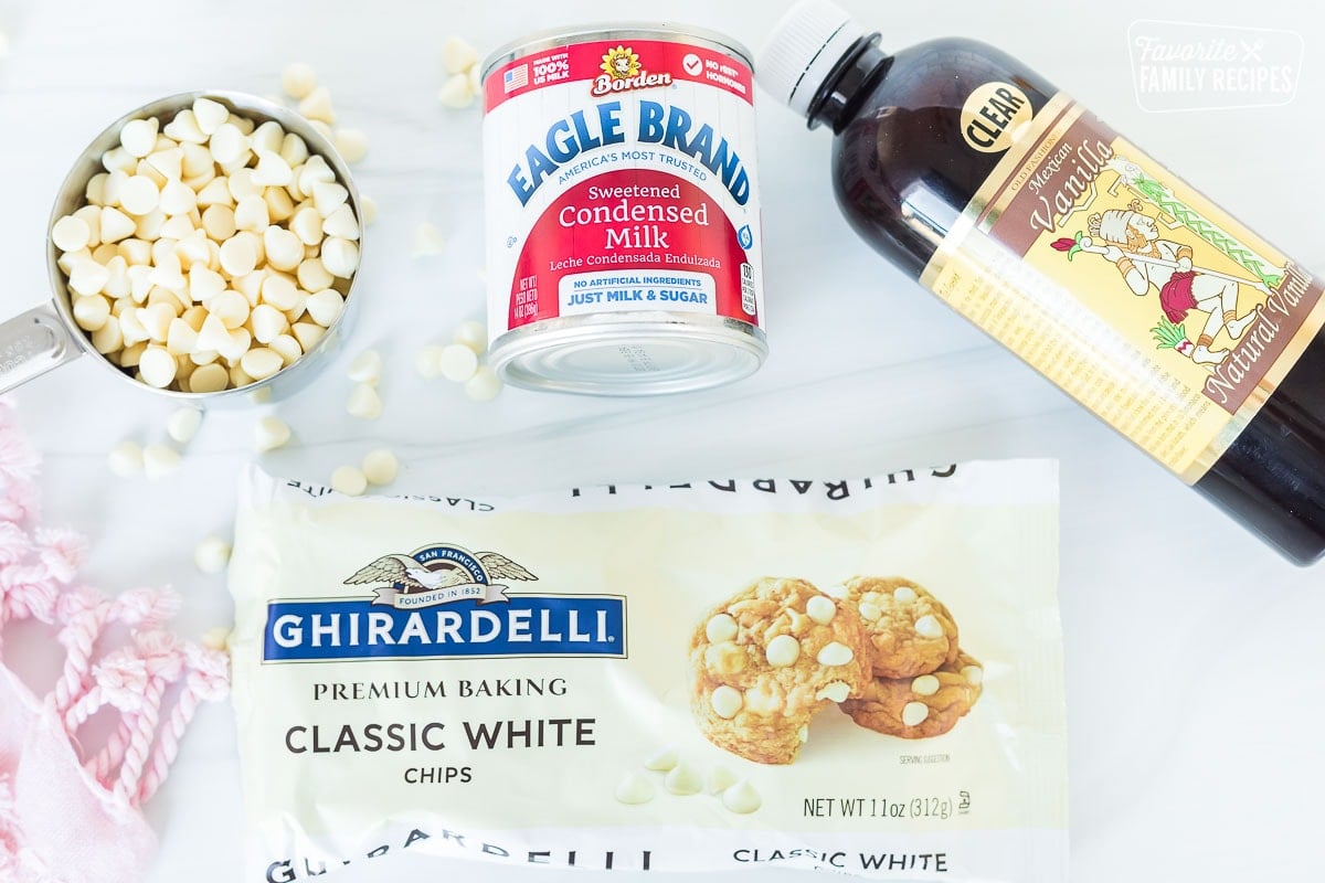 Ingredients to make vanilla fudge including vanilla, condensed milk, and white chocolate baking chips.