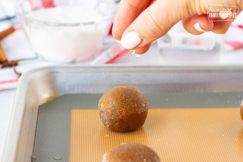 Hand sprinkling water onto a Molasses Cookie dough ball.