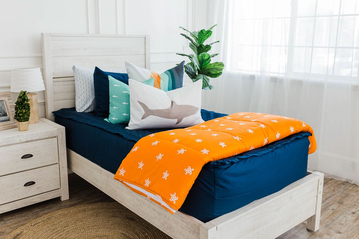 Beddy's boy bedding with dark blue covers and orange accents with sharks