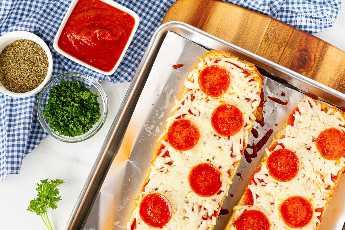 Two halves of French Bread Pizza on a covered cookie sheet.