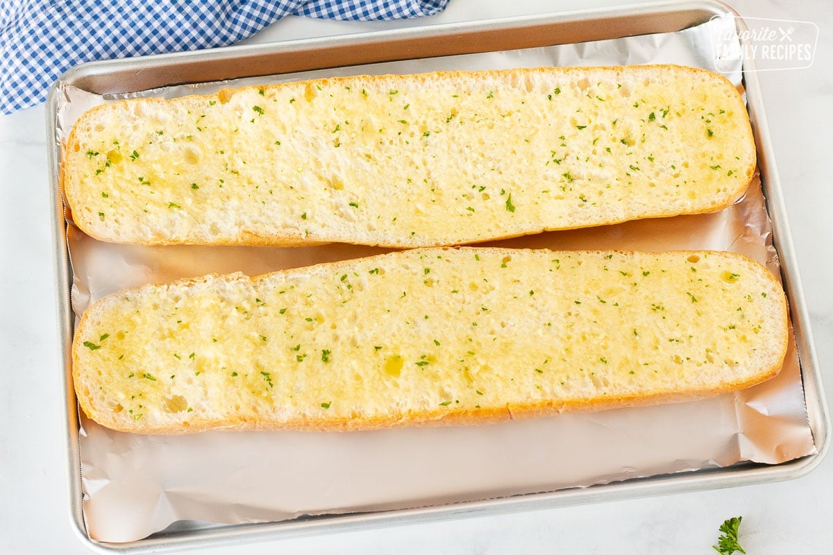 Two halves of French bread covered with butter mixture.