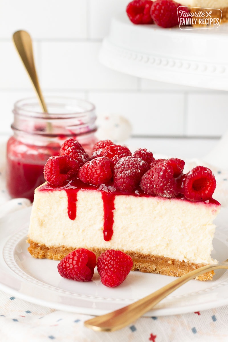 Close up slice of Raspberry coulis on cheesecake with fresh raspberries.