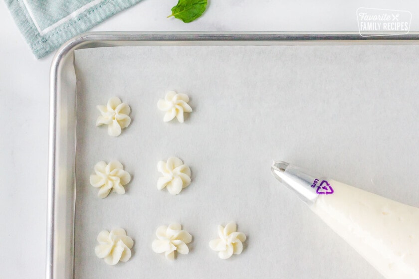 Cookie sheet covered with parchment paper and pipped flowers of Butter Mints with Cream Cheese.