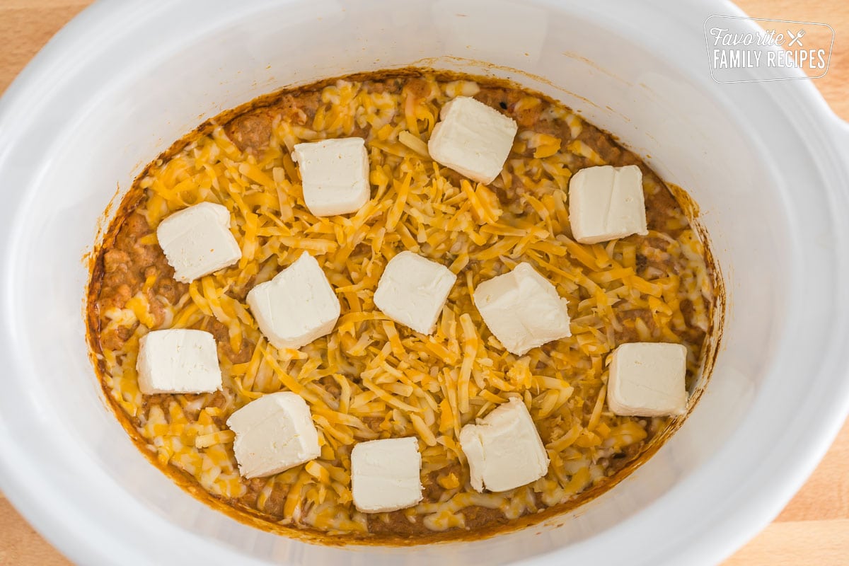 crockpot taco dip topped with cream cheese and shredded cheese