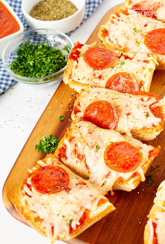 French Bread Pizza cut into slices on a cutting board.