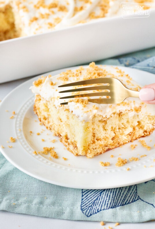 Fork cutting into a slice of Cinnamon Roll Cake on a plate.