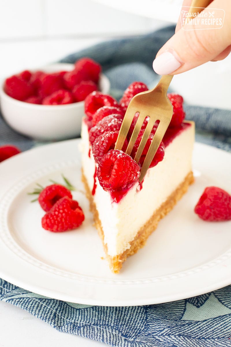 Fork cutting into a lice of Raspberry Cheesecake.