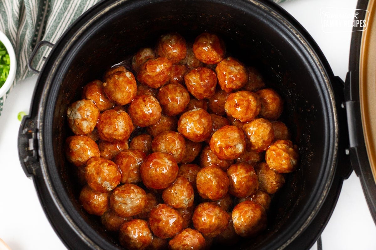 Slow Cooker with frozen Cocktail Meatballs covered in sauce.