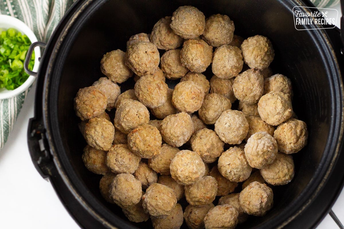 Slow cooker with frozen meatballs inside for Cocktail Meatballs.