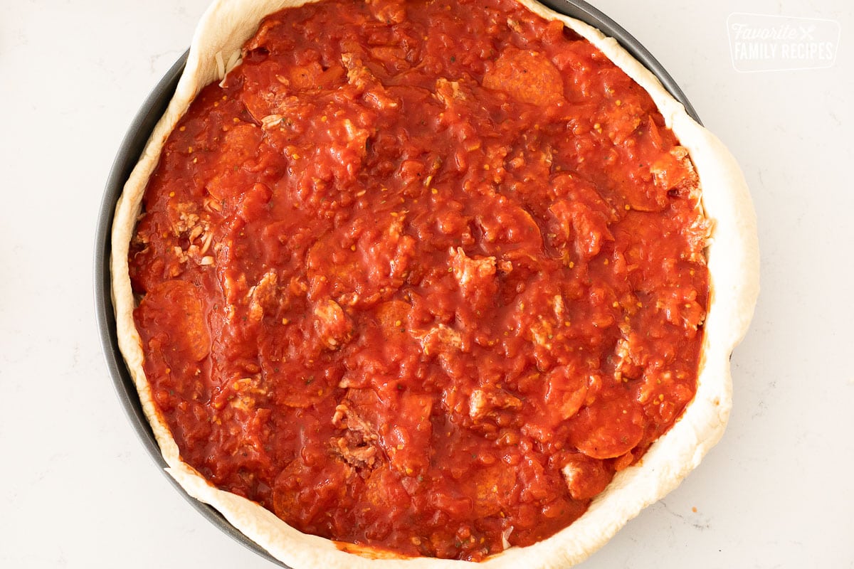 An uncooked Chicago style deep dish pizza like Gino's East with sauce over the top