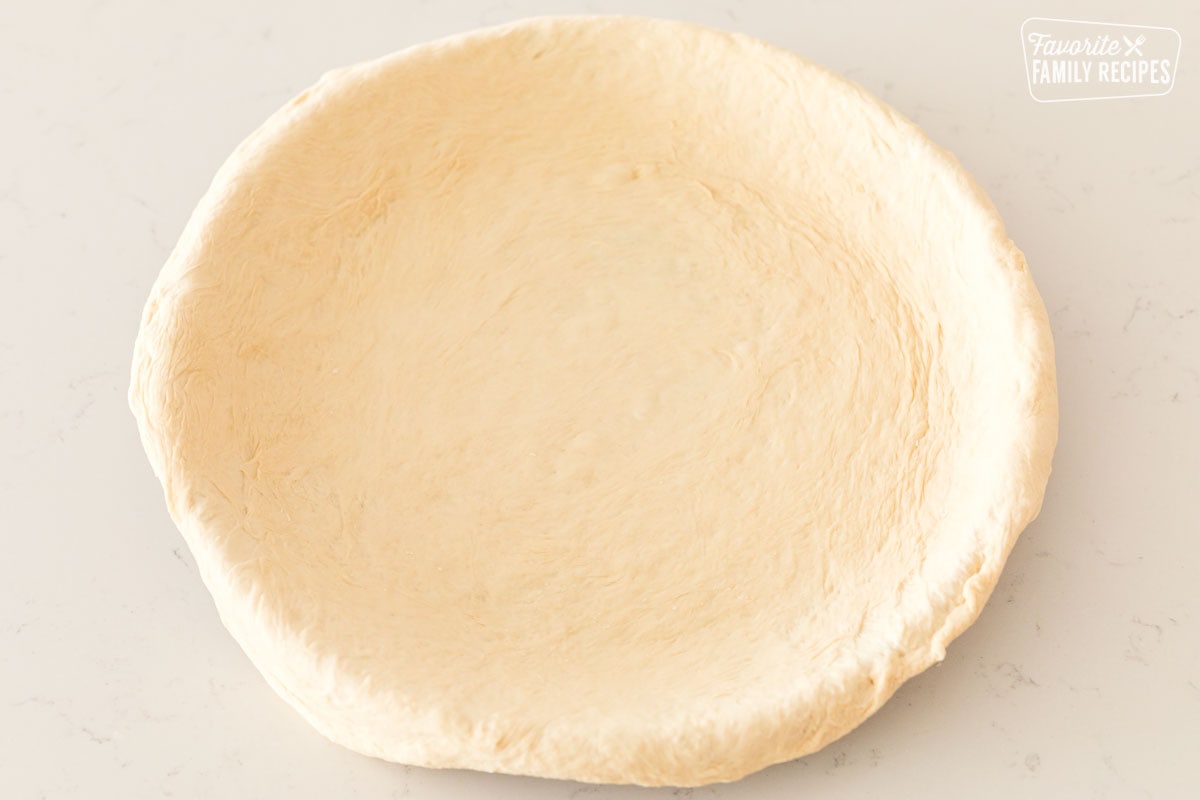 A plain uncooked deep dish pizza crust