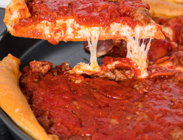 A Chicago-style deep dish pizza slice like Ginos East being pulled from a pan