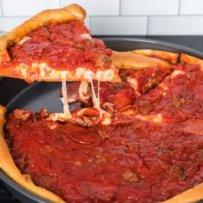 A slice of Chicago style deep dish pizza being lifted from a deep dish pan