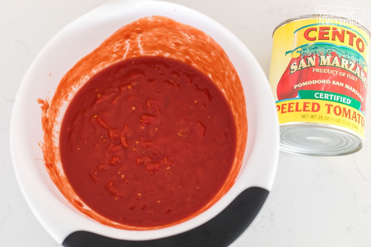 A bowl with tomatoes that have been crushed by hand.