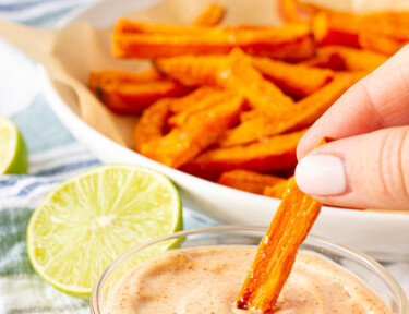 Dipping a Sweet Potato Fry into sauce. Limes on the side.