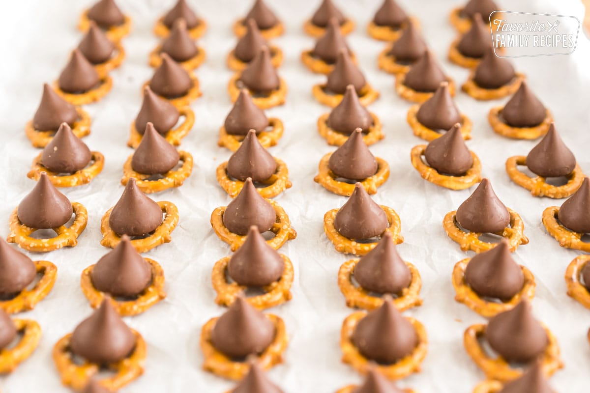 Pretzels on a baking sheet each topped with a hershey kiss.