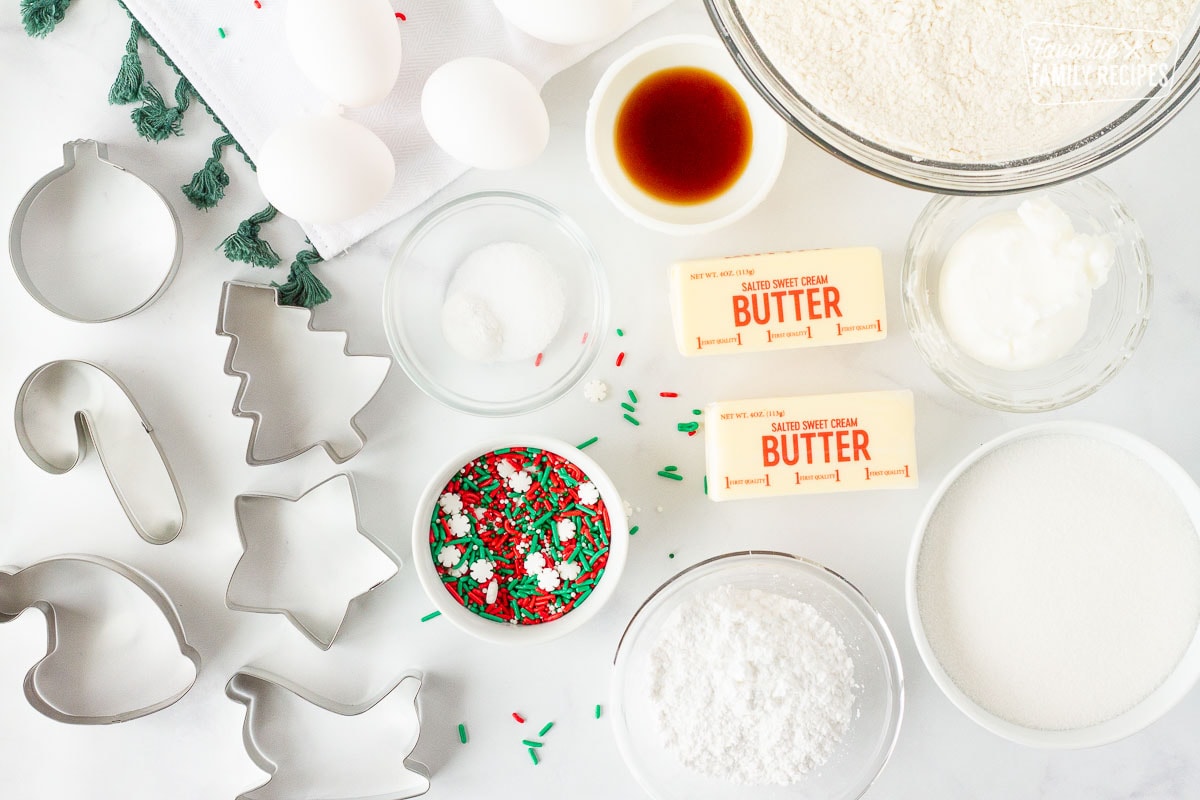 Flour, sugar, butter, crisco, vanilla, eggs, sprinkles, cookie cutters, sprinkles and dry ingredients for Christmas Sugar Cookies.