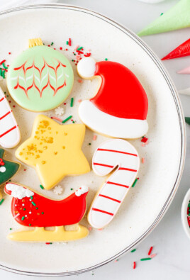 Plate of Christmas Sugar Cookies next to bags of royal icing and sprinkles.