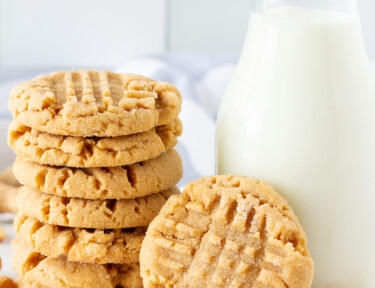 Large stack of Peanut Butter Cookies next to a glass of milk.
