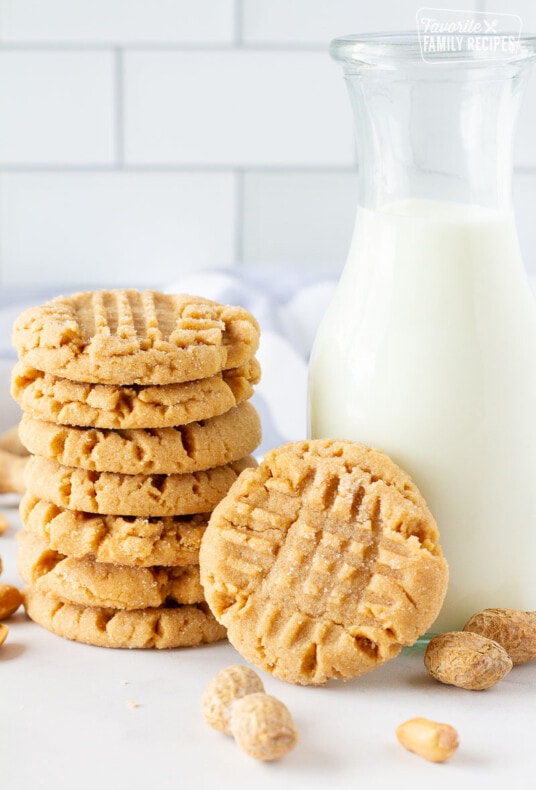 Large stack of Peanut Butter Cookies next to a glass of milk.