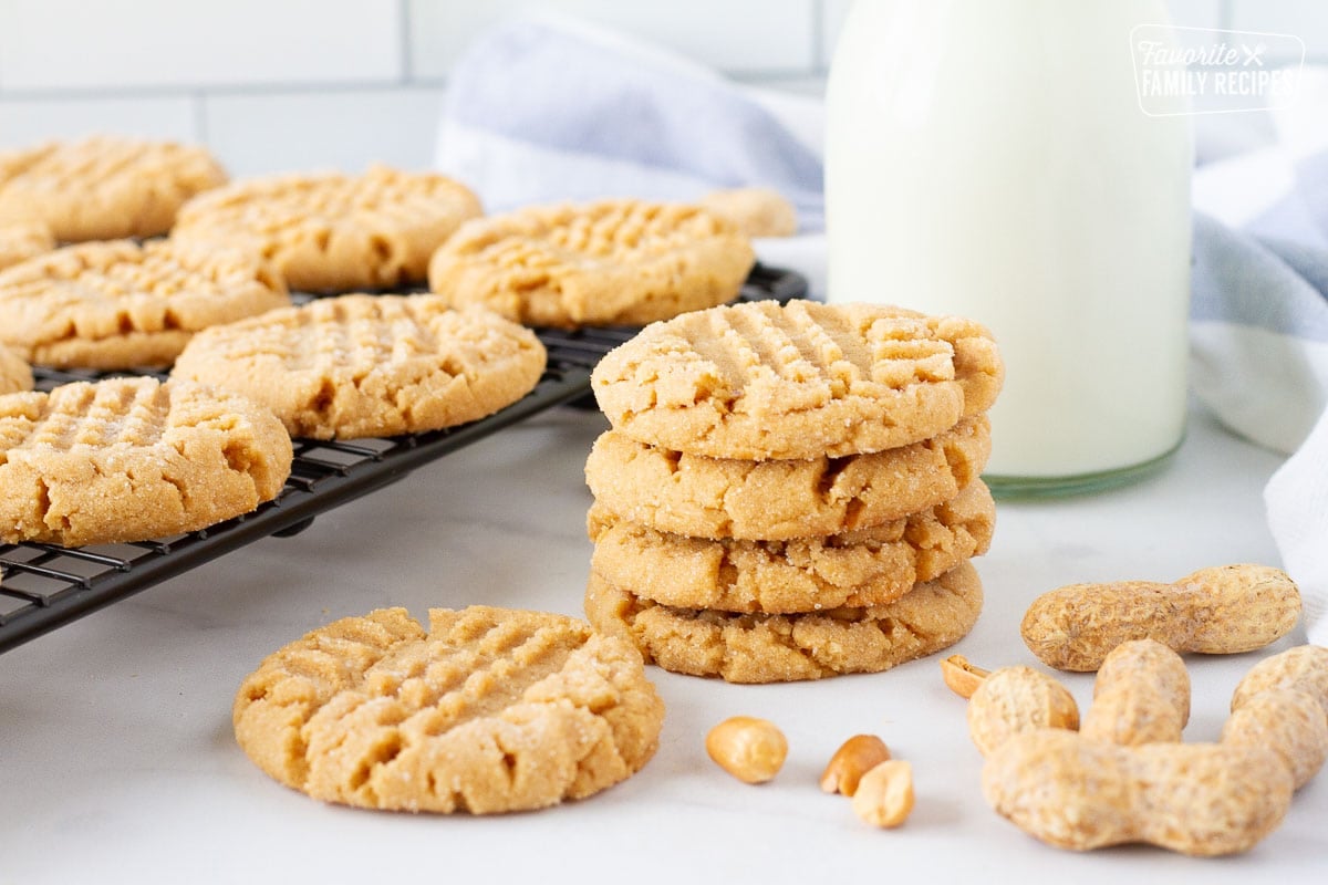 Cooling rack next to stack of Peanut Butter Cookies with milk.