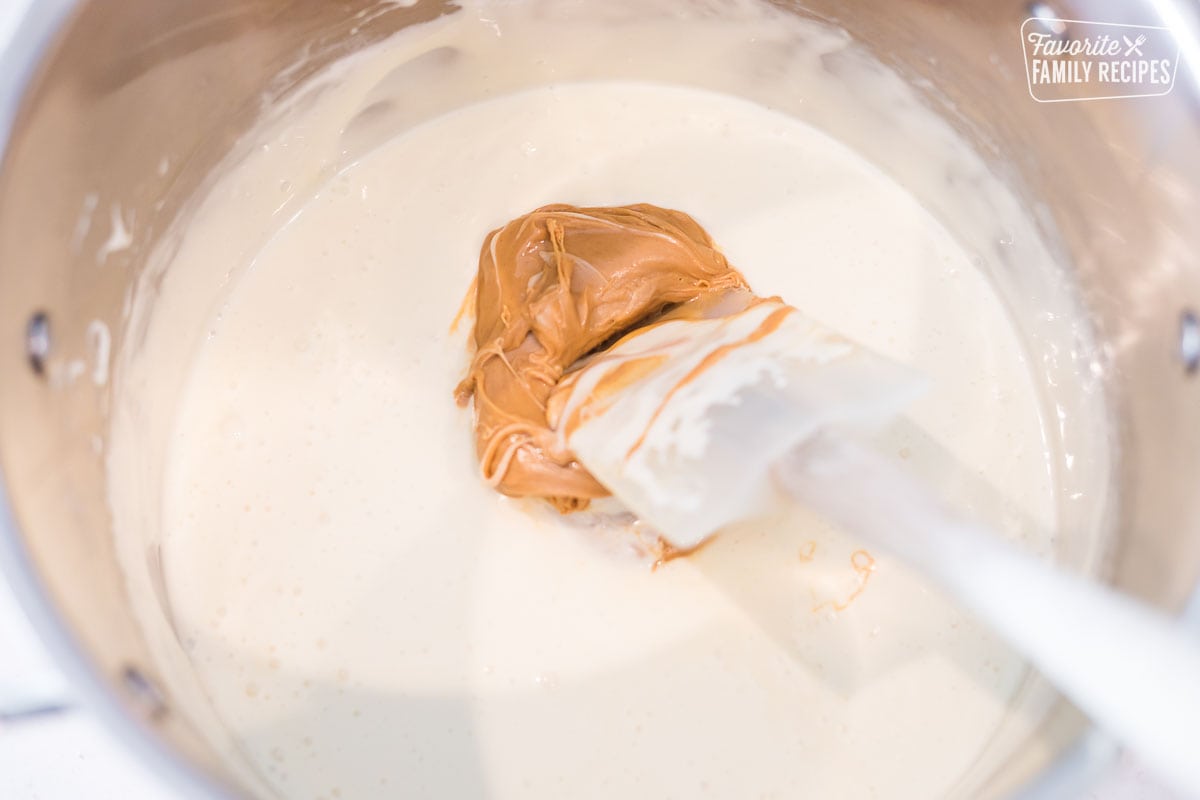 Peanut butter being added to melted marshmallows in a large pot