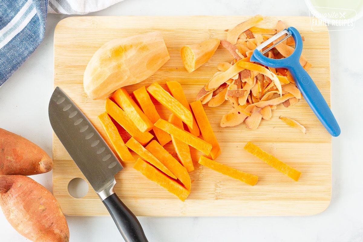 Cutting board with peeling and cutting sweet potatoes into fry shape.