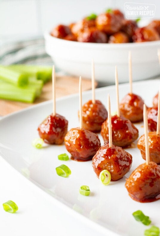 Cocktail Meatballs with toothpicks on a plate garnished with green onions.