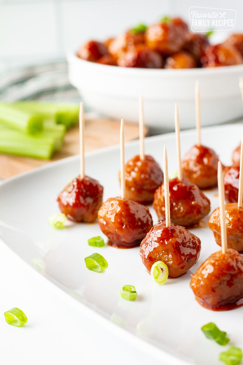 Cocktail Meatballs with toothpicks on a plate garnished with green onions.