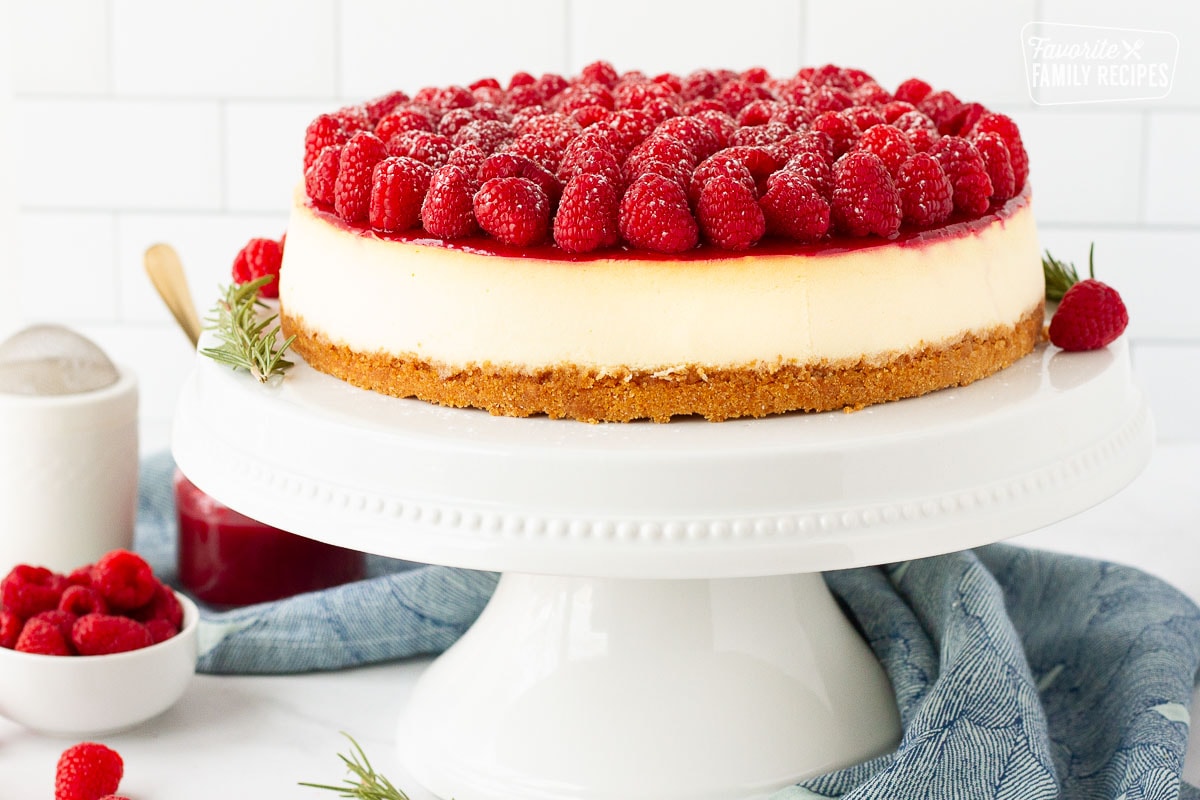 Whole Raspberry cheesecake on a cake stand.