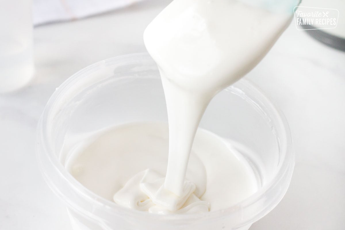 Spatula of Flood Royal Icing going into a bowl of Icing.