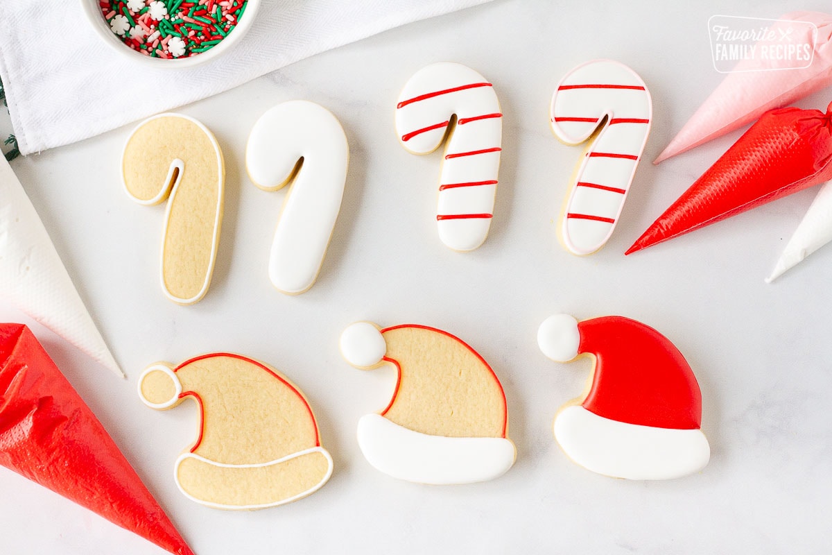 Decorated candy cane and Santa hat Christmas Sugar Cookies with bags of royal icing.