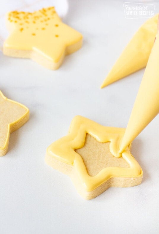 Filling in the second row of a star shaped cookie with Flood Royal Icing.