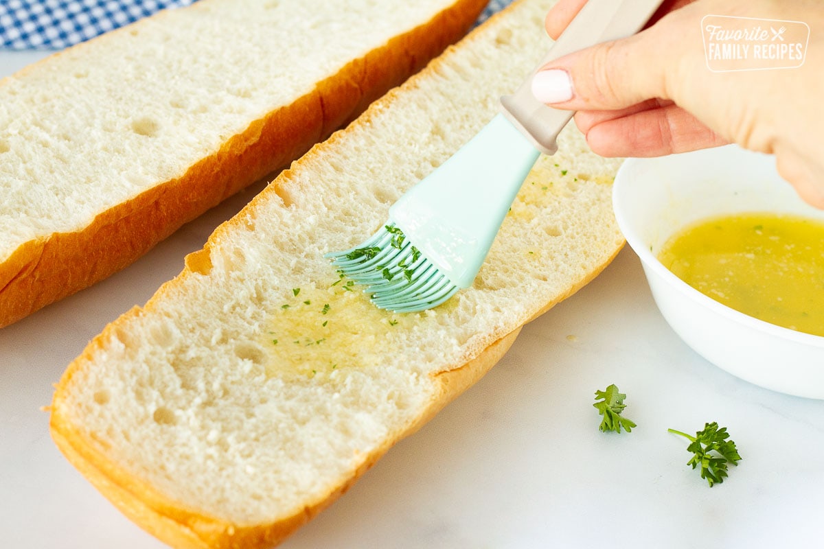 Spreading butter with brush on top of sliced French bread for Pizza.