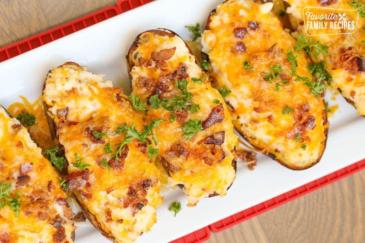 Twice baked potatoes on a platter topped with cheese and bacon bits