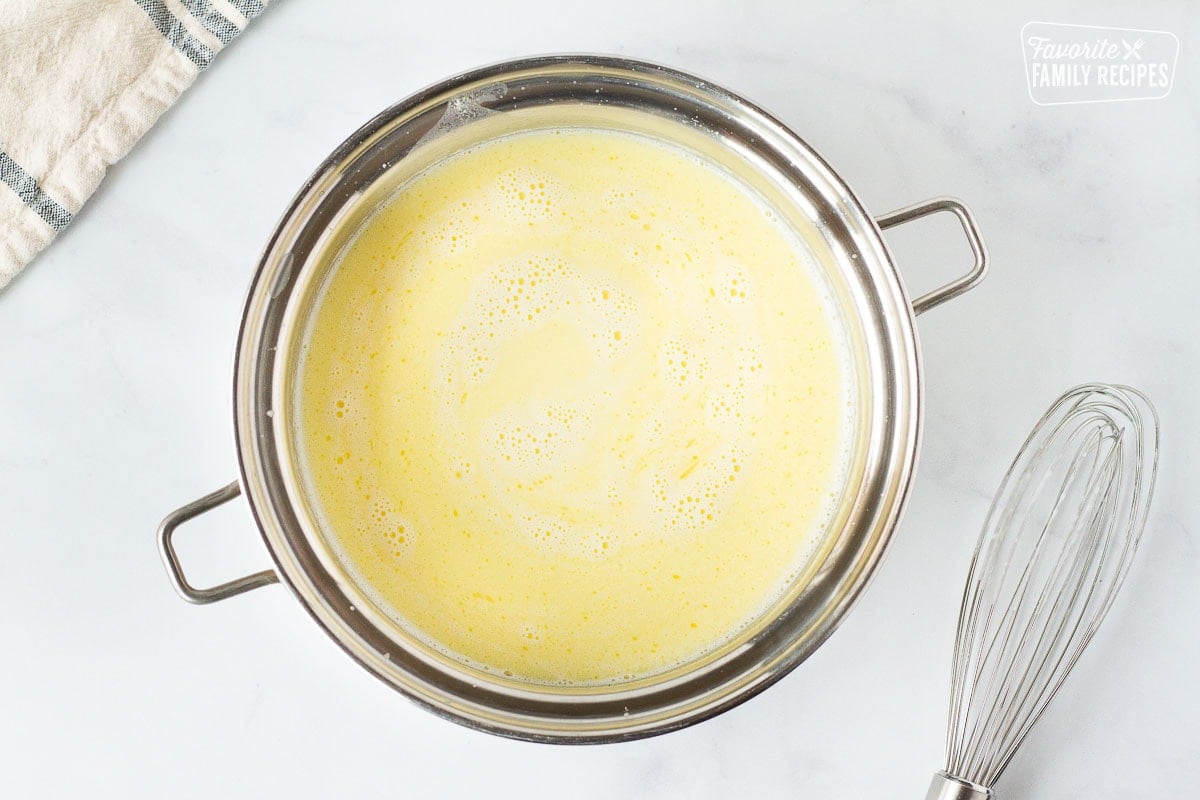 Butter and cream in a pot next to a whisk for Chicken Cordon Bleu Sauce.