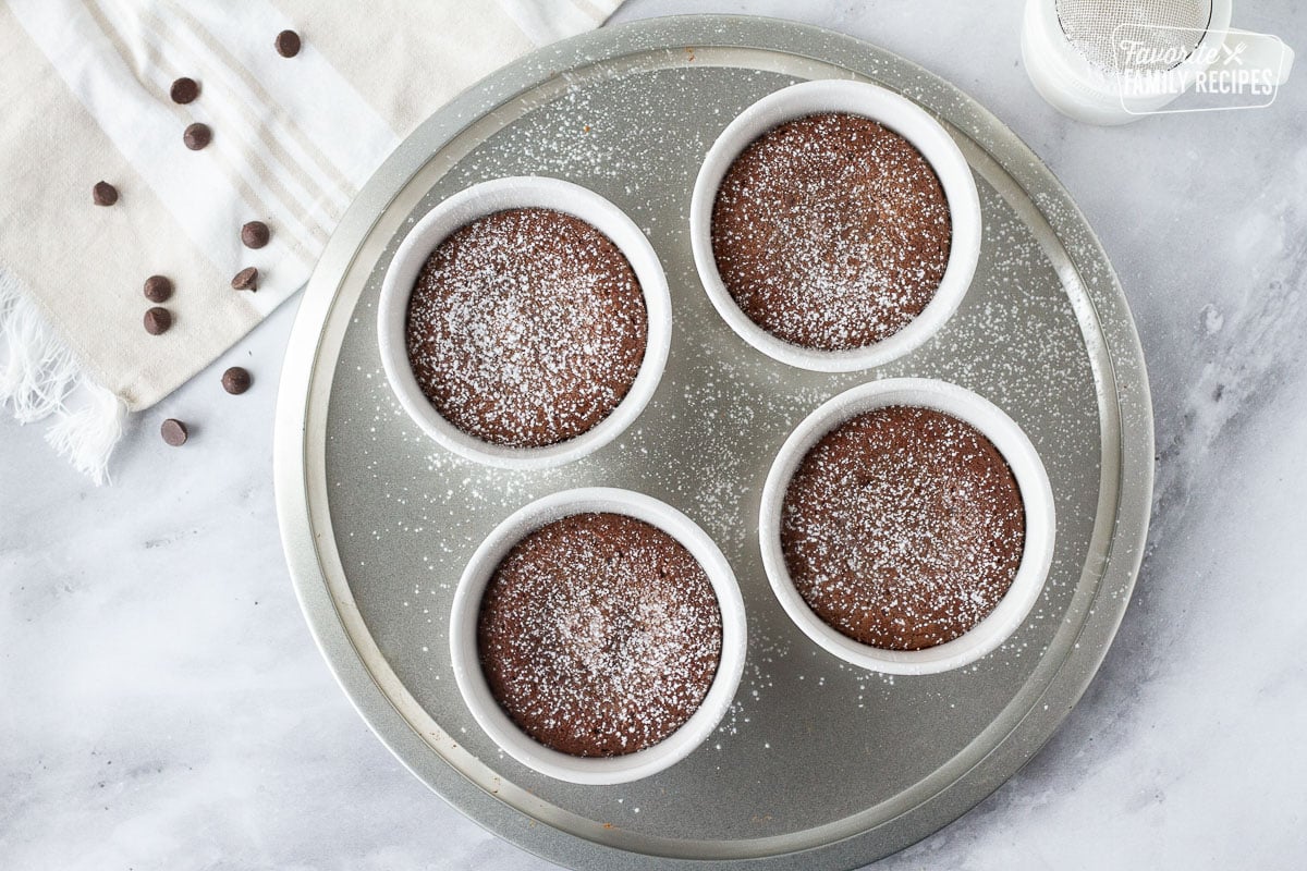 Four ramekins of baked Carnival Cruise Melting Chocolate Cake dusted with powdered sugar.