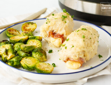 Roasted brussel sprouts and two Chicken Cordon Bleus on a plate next to the instant pot.