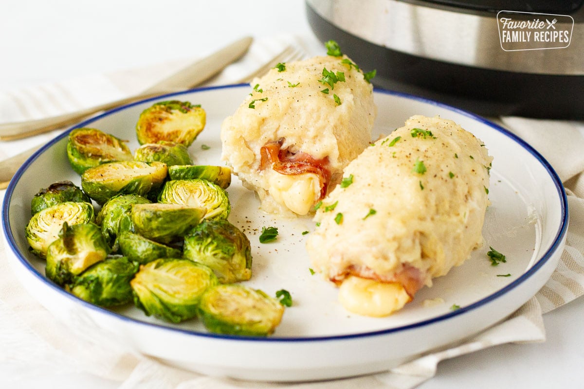 Roasted brussel sprouts and two Chicken Cordon Bleus on a plate next to the instant pot.