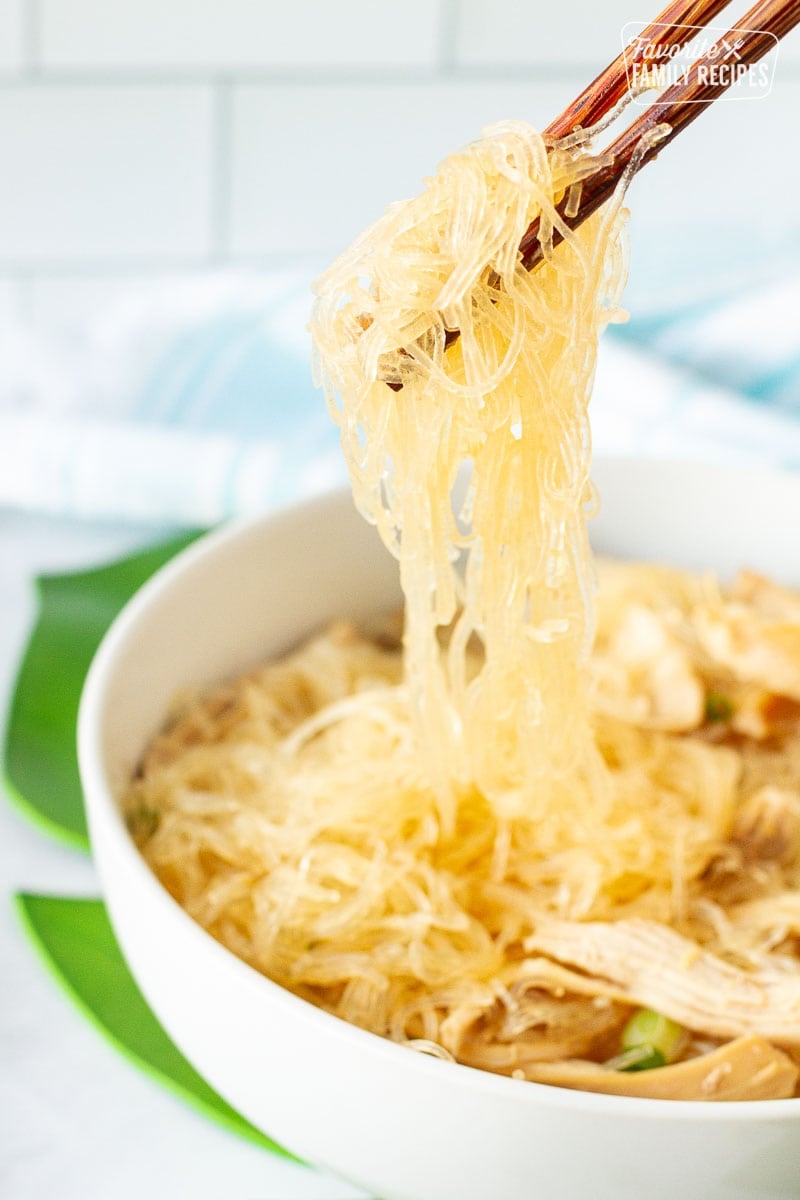 Chopsticks grabbing noodles from a bowl of Hawaiian Style Chicken Long Rice Noodles.