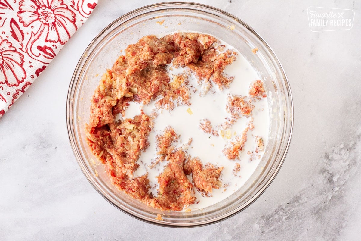 Bowl of meat mixture with cream on top for Frikadeller (Danish Meatballs).