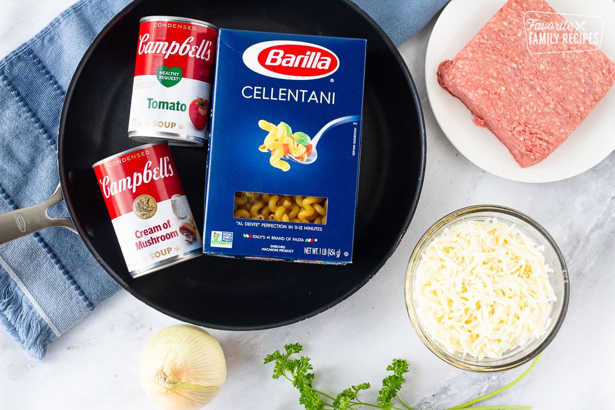Ingredients to make Creamy Ground Beef and Noodles Skillet including ground beef, cellentani noodles, tomato soup, cream of mushroom soup, onion and shredded cheese.