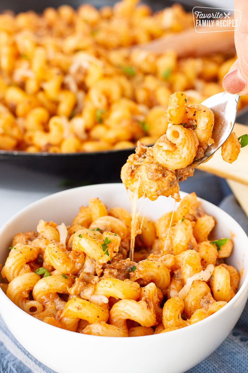 Fork pulling a cheesy bite of Creamy Ground Beef and Noodles Skillet.