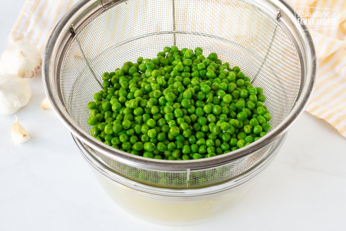 Peas straining in a colander excess butter for cooking Frozen Peas.